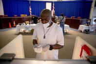 Darren Atkinson wears a mask as he wipes down a voting booth at a voting center during primary voting in Washington, Tuesday, June 2, 2020. (AP Photo/Andrew Harnik)