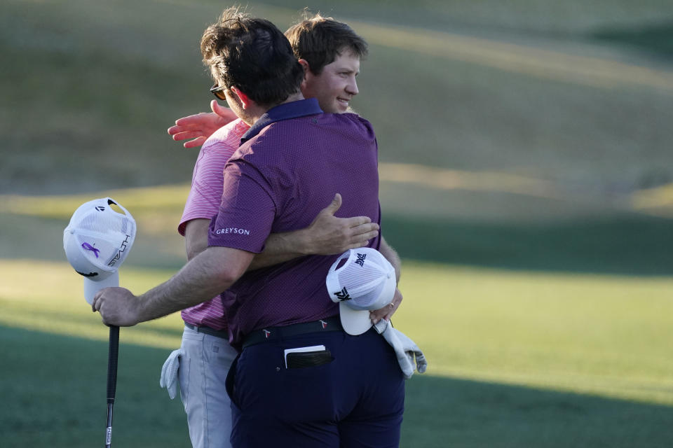 Hudson Swafford (facing camera) hugs playing partner Harry Higgs on the 18th hole during the final round of the American Express golf tournament on the Pete Dye Stadium Course at PGA West, Sunday, Jan. 23, 2022, in La Quinta, Calif. (AP Photo/Marcio Jose Sanchez)