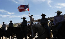 A supporter of the Bundy family flies the American flag after the Bureau of Land Management agreed to release the Bundy's cattle near Bunkerville, Nev. April 12, 2014. (AP Photo/Las Vegas Review-Journal, Jason Bean)