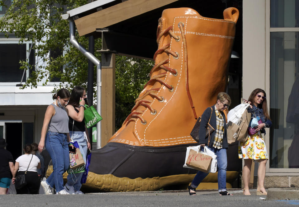 Shoppers walk past a giant LL Bean boot outside the Ross Park Mall in Pittsburgh Sunday, May 23, 2021. With vaccinations rolling out and shoppers freer to go out maskless, retailers are seeing an eager return to their stores after months of watching their customers focus on online buying during the pandemic. (AP Photo/Gene J. Puskar)