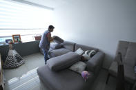 Domestic worker Gabriela Flores straightens the cushions on couch in a living area at her workplace in Mexico City, Sunday, May 19, 2024. Flores is among approximately 2.5 million Mexicans — largely women — who serve as domestic workers in the Latin American nation. (AP Photo/Marco Ugarte)