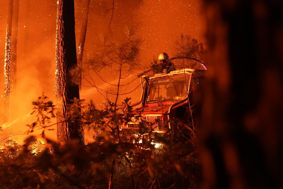 This photo provided by the fire brigade of the Gironde region SDIS 33, (Departmental fire and rescue service 33) shows firefighters tackling a blaze near Hostens, south of Bordeaux, southwestern France, Wednesday, Aug. 10, 2022. (SDIS 33 via AP)