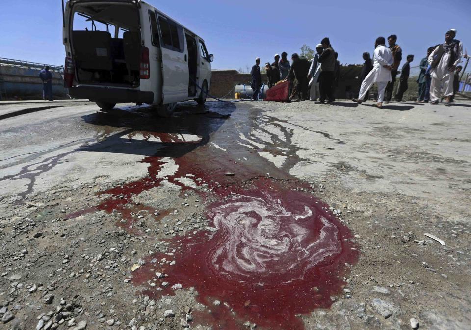 Afghan residents watch as a man washes a damaged minivan after was hit by a remote-controlled bomb in Kabul July 15, 2014. A remote-controlled bomb planted at the side of a road hit a government employee's vehicle, killing two people and wounding five, a police officer said. (REUTERS/Omar Sobhani)