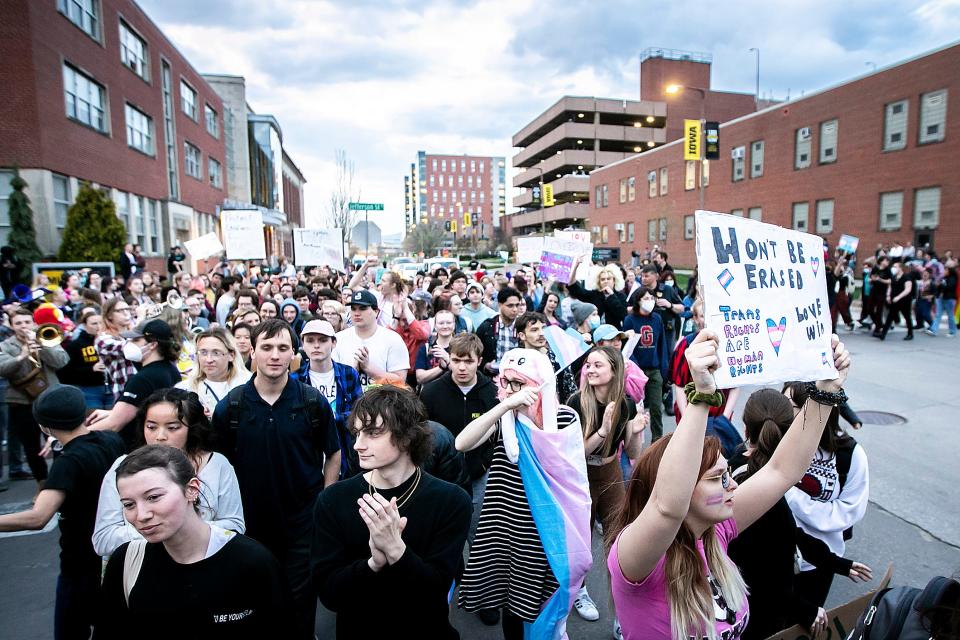 A transgender-rights protester holds a sign reading "We won't be erased" and "Trans rights are human rights" as they march in the intersection of Jefferson and Madison Streets blocking traffic as Matt Walsh speaks at an event hosted by the Young America's Foundation, Wednesday, April 19, 2023, at the Iowa Memorial Union on the University of Iowa campus in Iowa City, Iowa.