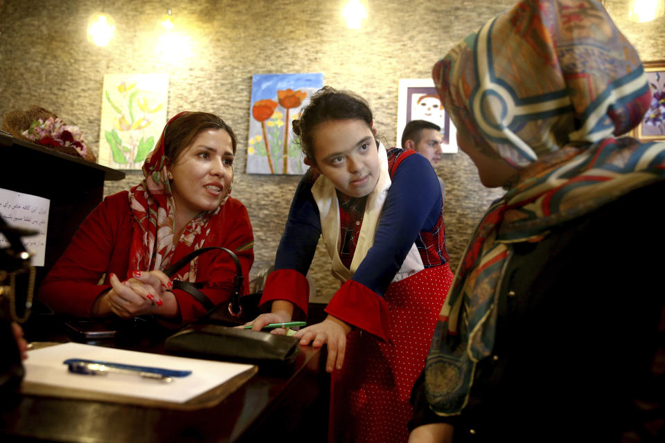 In this Monday, Aug. 6, 2018, photo, cafe staff person Melika Aghaei, 14, center, with down syndrome takes an order in Downtism Cafe in Tehran, Iran. The popular cafe, whose name combines “Down” with “autism,” in Tehran’s bustling Vanak Square is entirely run by people with Down syndrome or autism. More than just providing meaningful work, the cafe is helping break down barriers by highlighting how capable people with disabilities are. (AP Photo/Ebrahim Noroozi)