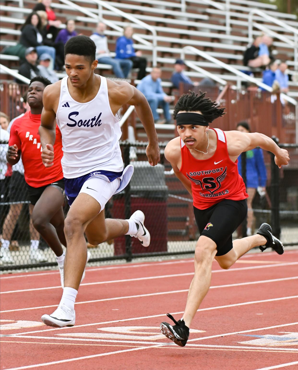 Bloomington South’s Khaliq Akou runs alongside Southport’s Devin Wilson in the boys' 100 meter dash prelims during the Conference Indiana track meet at Bloomington North on Friday, April 26, 2024.