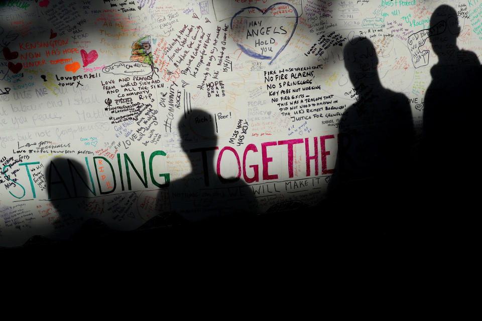 <p>Shadows of people looking at messages of condolence for the victims on a wall near to the site of the Grenfell Tower fire on June 15, 2017 in London, England. (Photo: Dan Kitwood/Getty Images) </p>