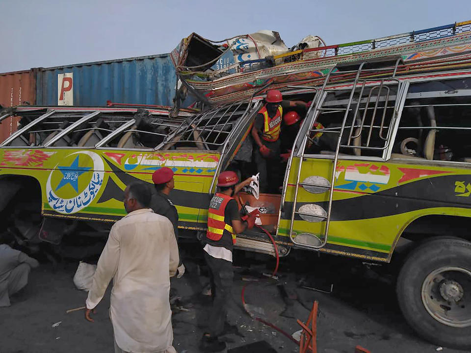 In this handout photo released by Punjab Province's Emergency Service Rescue 11222, shows rescue workers at the site of a deadly bus accident near Dera Ghazi Khan, Pakistan, Monday, July 19, 2021. The speeding bus carrying mostly laborers traveling home for a major Muslim holiday rammed into a container truck on a busy highway in central Pakistan, killing and injuring dozens, police and rescue officials said. (Emergency Service Rescue 1122 via AP)