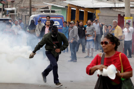 A demonstrator runs to throw a tear gas canister back to the police, during a protest against the re-election of Honduras' President Juan Orlando Hernandez in Tegucigalpa, Honduras January 20, 2018. REUTERS/Jorge Cabrera