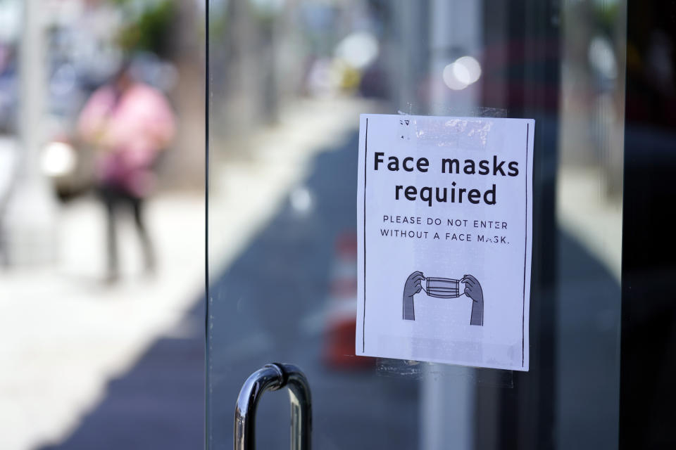 FILE - A sign advises shoppers to wear masks outside of a story Monday, July 19, 2021, in the Fairfax district of Los Angeles. Los Angeles County has reinstated an indoor mask mandate due to rising COVID-19 cases. (AP Photo/Marcio Jose Sanchez)