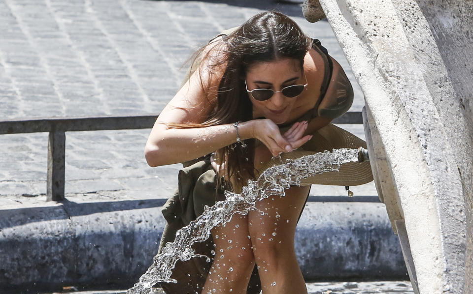 A woman drinks at the Barcaccia fountain, built between 1627 and 1629 by Pietro Bernini, possibly with the help of his son Gian Lorenzo, in downtown Rome, Friday, July 31, 2020. The first heat wave of the summer will last at least until Saturday, bringing temperatures over 34 Celsius (104 Fahrenheit). (AP Photo/Riccardo De Luca)
