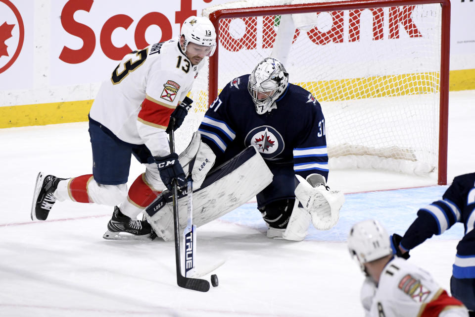 Winnipeg Jets goaltender Connor Hellebuyck (37) makes a save on Florida Panthers' Sam Reinhart (13) during the second period of an NHL hockey game, Tuesday, Jan. 25, 2022 in Winnipeg, Manitoba. (Fred Greenslade/The Canadian Press via AP)