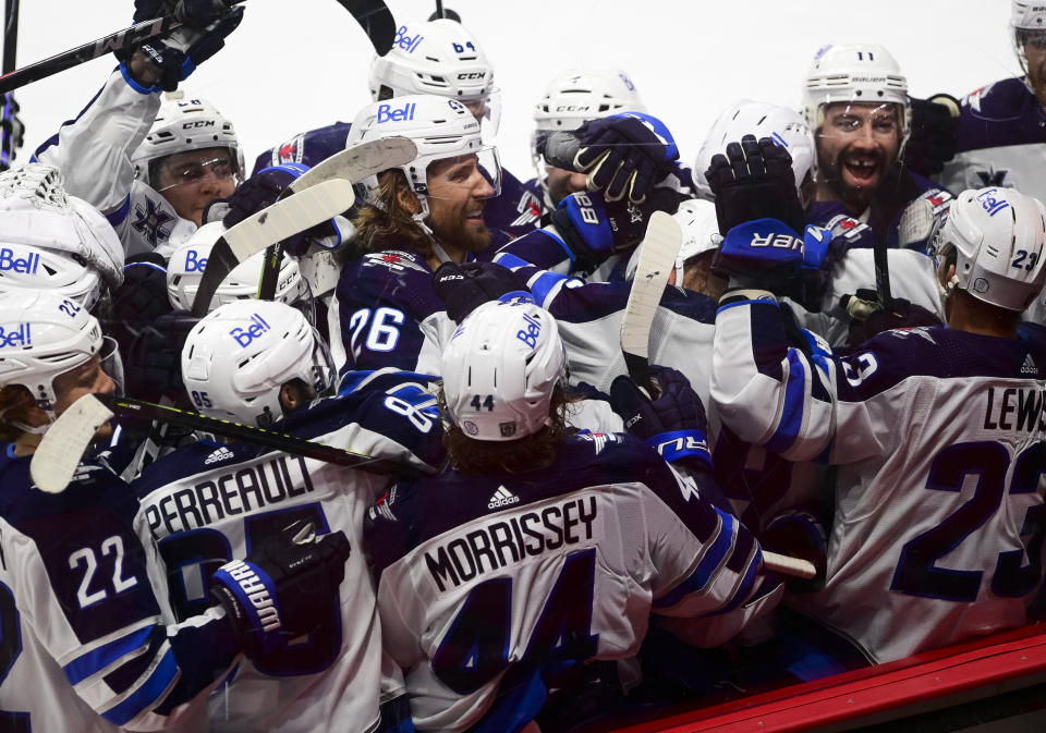 Winnipeg Jets players gather around Nikolaj Ehlers (27) after he scored the game-winning goal past Ottawa Senators goaltender Matt Murray in overtime of an NHL game in Ottawa, Ontario, on Tuesday, Jan. 19, 2021. (Sean Kilpatrick/The Canadian Press via AP)