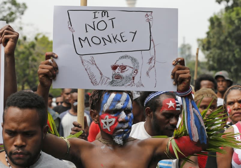 A Papuan students with faces painted with the colors of the separatist 'Morning Star' flag holds up a poster during a rally near the presidential palace in Jakarta, Indonesia, Wednesday, Aug. 28, 2019. A group of West Papuan students in Indonesia's capital staged the protest against racism and called for independence for their region. (AP Photo/Tatan Syuflana)