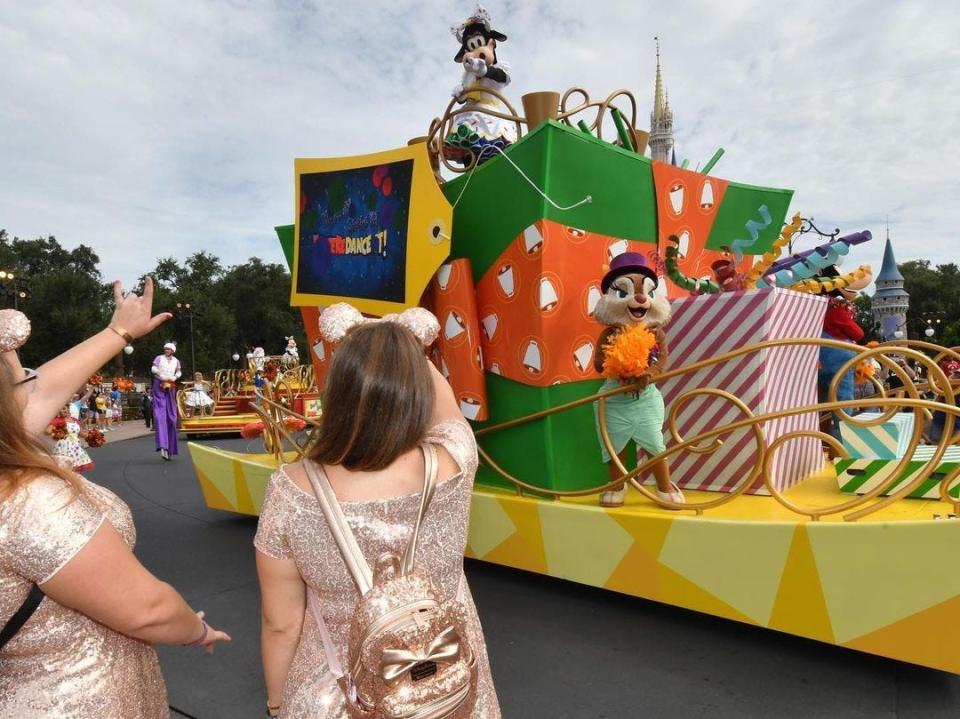 casey and a friend waving at characters passing by in a cavalcade at disney world