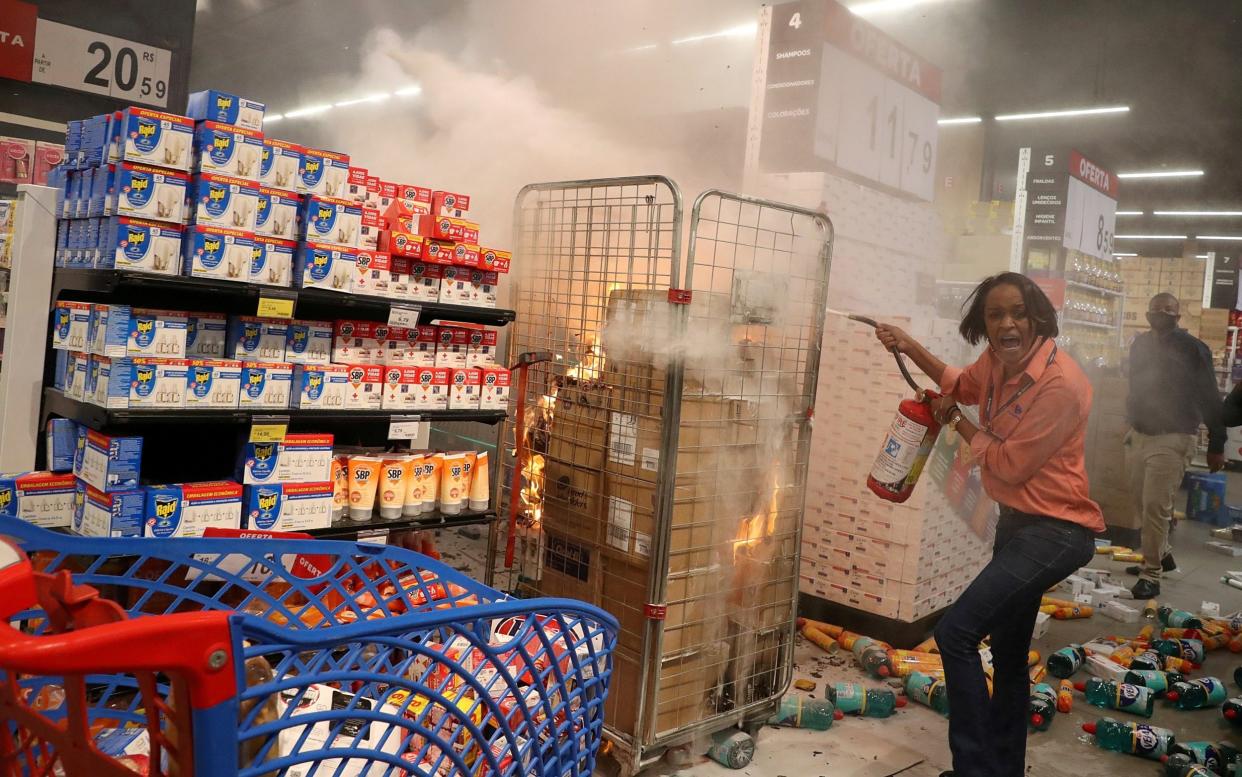 A woman attempts to put out a fire at a vandalised Carrefour store during a march in Sao Paulo - REUTERS/Amanda Perobelli