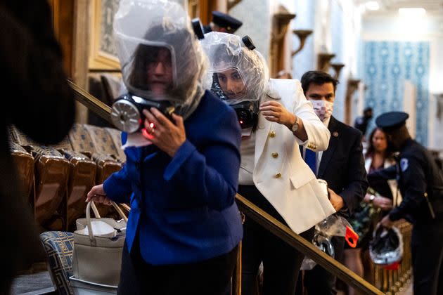 Reps. Sara Jacobs (D-Calif.), center, and Annie Kuster (D-N.H.), left, take cover as rioters attempt to disrupt the joint session of Congress to certify the Electoral College vote on Jan. 6, 2021.