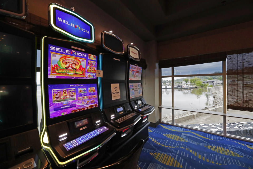 Two video slot machines await players while one in the middle sits out of service at the WaterView Casino and Hotel in Vicksburg, Miss., Thursday, May 21, 2020. Following a two-month shutdown due to coronavirus, casinos statewide are allowed to reopen Thursday, amid enhanced restrictions to keep customers and employees safe. (AP Photo/Rogelio V. Solis)