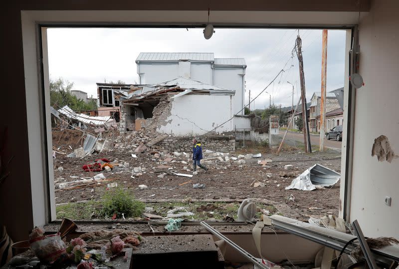 A man walks past a house damaged by recent shelling during the military conflict over the breakaway region of Nagorno-Karabakh, in Stepanakert