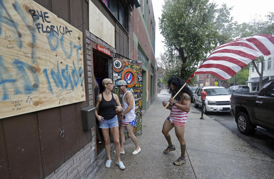 Jeff Egyp carries an American flag as he arrives at the Barbary Coast bar in downtown Wilmington, N.C., as the Florence threatens the coast Thursday, Sept. 13, 2018. (AP Photo/Chuck Burton)