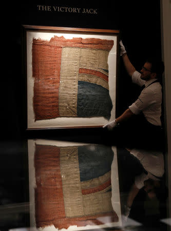 FILE PHOTO: A member of Sotheby's staff poses for a photograph with a large fragment of Lord Nelson's union flag which flew from the HMS Victory during the Battle of Trafalgar London, Britain January 11, 2018. REUTERS/Peter Nicholls/File Photo