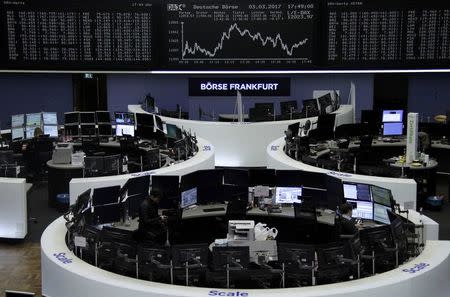 Traders work at their desks in front of the German share price index, DAX board, at the stock exchange in Frankfurt, Germany, March 3, 2017. REUTERS/Staff/Remote