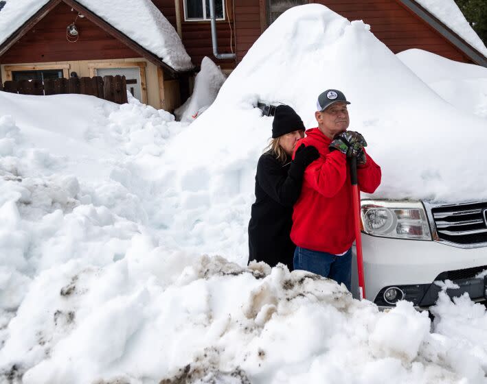 CRESTLINE, CA - MARCH 6, 2023: Deanna Beaudoin leans on Don Kendrick while taking a break from shoveling out their car on March 6, 2023 in Crestline, California. They have been snowed-in for 12 days. Kendrick had to walk a couple miles to the store to pick up Beaudoin's medication after recent storms dropped more than 100 inches of snow in the San Bernardino Mountains.(Gina Ferazzi / Los Angeles Times)