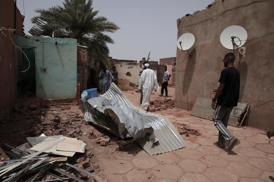 People walk by a house hit in recent fighting in Khartoum, Sudan, Tuesday, April 25, 2023.