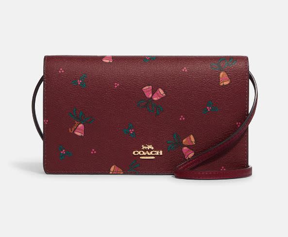 Clutch cruzado Anna de Coach con estampado de campanas navideñas. (Foto: Coach Outlet)