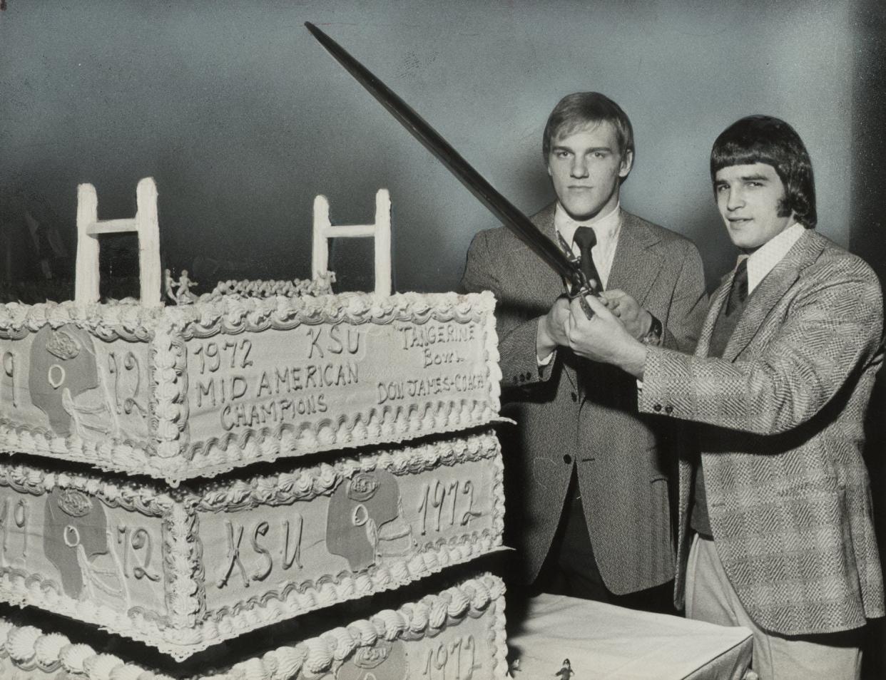 Kent State University football stars Jack Lambert (left) and Gary Pinkel pose for a photo at the team's postseason banquet in front of a cake celebrating the Golden Flashes winning the 1972 Mid-American Conference championship.