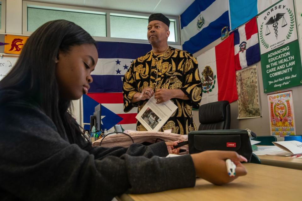 Teacher Donald Singleton speaks as a student reviews the class material.