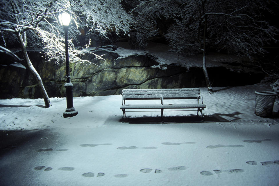 snow on the ground in a park at night with footprints.