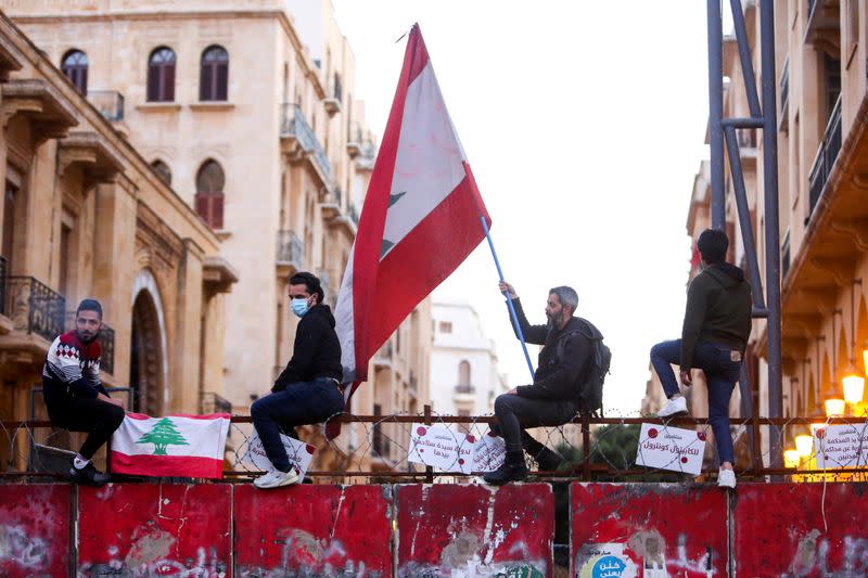 FILE PHOTO: A demonstrator holds a Lebanese flag during a protest against the fall in Lebanese pound currency and mounting economic hardships, in Beirut, Lebanon March 12, 2021