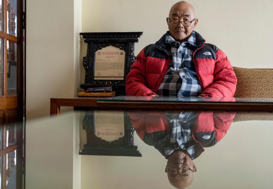Kanchha Sherpa, who helped the first team conquer Mount Everest in 1953, sits in front of a table.