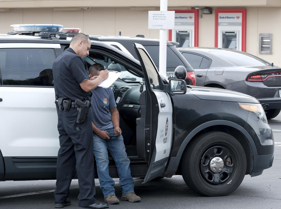 A LAPD officer talks to the victim of an attempted robbery in Los Angeles on Thursday, July 25, 2019. A gunman shot five people, killing three, in two attacks early Thursday in Los Angeles that police say took the lives of two of his family members and an acquaintance. A manhunt was underway for Gerry Dean Zarragoza, 26, who may be driving a blue Jeep Liberty with paper license plates, police spokesman Officer Drake Madison said. (David Crane/The Orange County Register via AP)