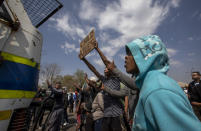 Protesters demonstrate outside a police station at Eldorado Park, Johannesburg, South Africa, Thursday, Aug. 27, 2020. Residents from the township, south of Johannesburg are demanding justice for a teenager shot and killed, allegedly at the hands of police Wednesday. (AP Photo/Themba Hadebe)