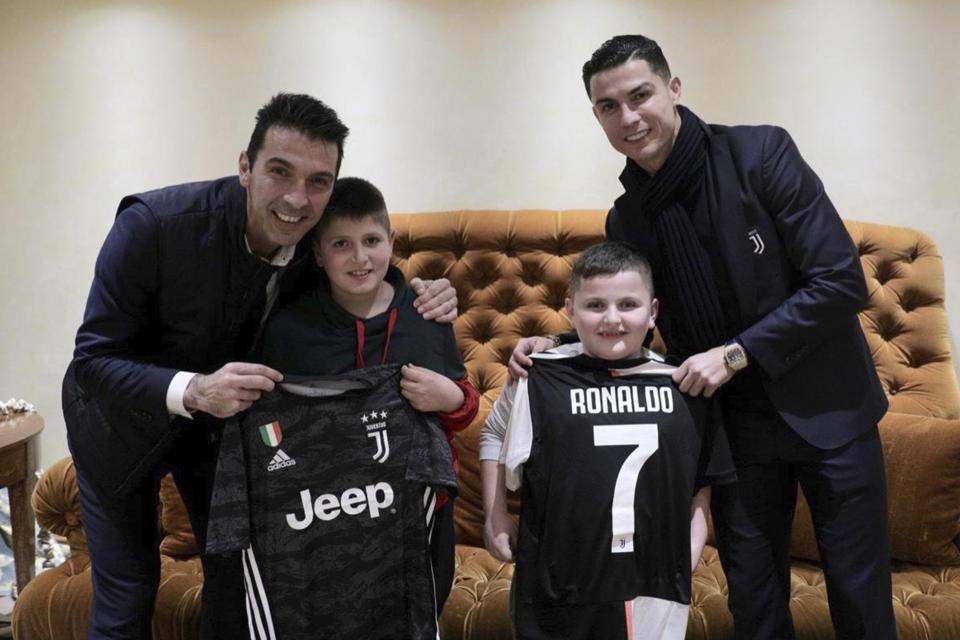 Juventus' players Cristiano Ronaldo, right, and Gianluigi Buffon, left, pose with Aurel Lala and Alesio Cakoni, in Rome on Friday, Dec. 6, 2019. The two Albanian children were injured when they escaped their collapsing flat jolted from the Nov. 26 6.4-magnitude earthquake, that killed 51 persons and injured more than 3,000 others. They lost each two family members but their dream came true when Prime Minister Edi Rama took them to Rome, Italy to meet with their sport idols Ronaldo and Buffon. (Albanian Prime Minster Office via AP)