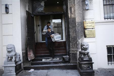 Workers carry stacks of newspaper from the steps of the damaged front of the Chinese consulate after an unidentified person set fire to the main gate in San Francisco, California January 2, 2014 REUTERS/Stephen Lam