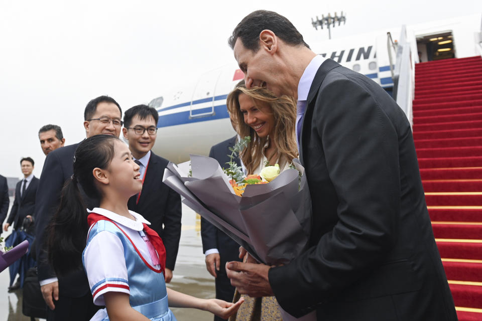 In this photo released by Xinhua News Agency, Syrian President Bashar Assad, right, and first lady Asma Assad receive a bouquet of flowers from a young girl as they arrive in Hangzhou, China, Thursday, Sept. 21, 2023. Assad arrived in Hangzhou to attend the opening ceremony of the 19th Asian Games. (Huang Zongzhi/Xinhua via AP)