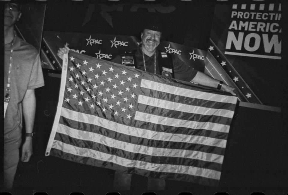 An attendee holds up an American flag in the main hall of CPAC after a speech in National Harbor, Md., on March 3, 2023. (Frank Thorp V / NBC News)