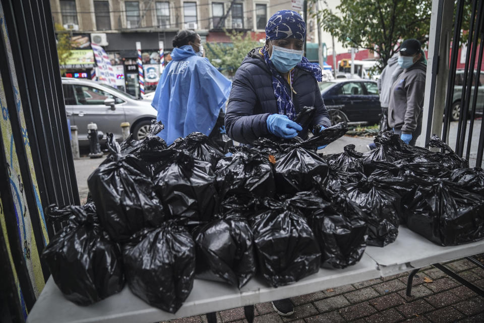 Volunteer Dolly Caulderon, center, prepares to hand out boxed meals prepared at the South Bronx restaurant La Morada, Wednesday Oct. 28, 2020, in New York. After a fund raising campaign during the coronavirus pandemic, La Morada, an award winning Mexican restaurant, reopened and now also functions as a soup kitchen, serving 650 meals daily. (AP Photo/Bebeto Matthews)