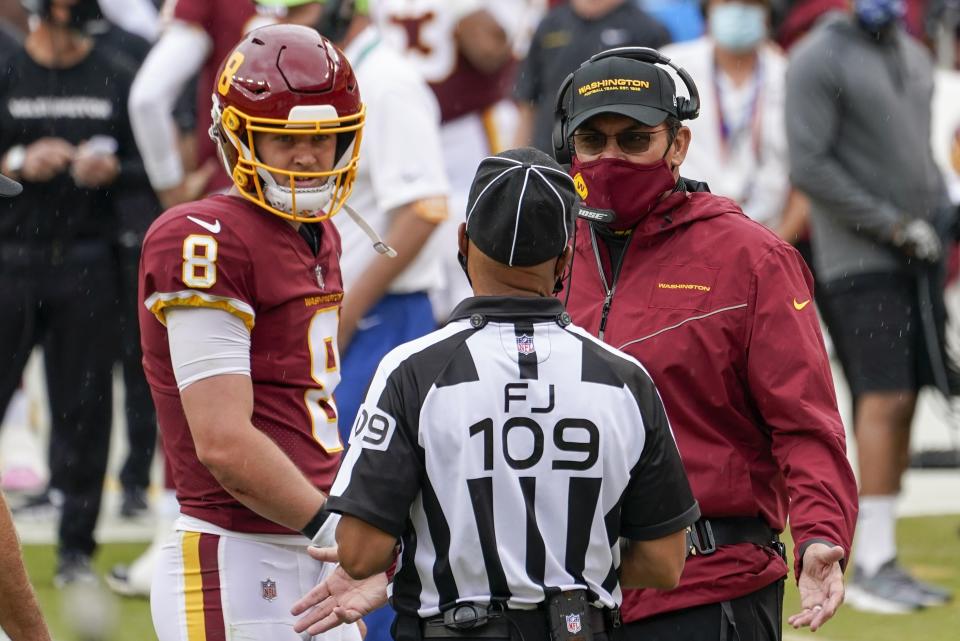 FILE - In this Sunday, Oct. 11, 2020 file photo, Washington Football Team head coach Ron Rivera and quarterback Kyle Allen talk to field judge Dale Shaw (104) during the first half of an NFL football game against the Los Angeles Rams in Landover, Md. The first game between 1-5 Washington and the 2-4 Dallas Cowboys since the name change is also the longtime NFC East rivals’ first meeting with this bad a combined winning percentage since 2001. That was a 9-7 game kicker Tim Seder won with a 26-yard field goal as time expired after a collision with a horse on the field during warmups. (AP Photo/Steve Helber, File)