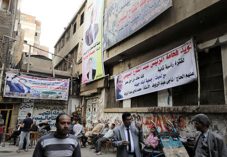 People walk under posters of Egyptian President Abdel Fattah al-Sisi for the upcoming presidential election, in Cairo, Egypt March 19, 2018. REUTERS/Mohamed Abd El Ghany