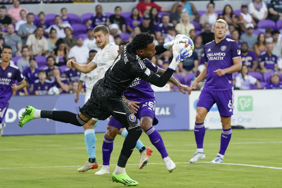 Orlando City goalkeeper Pedro Gallese, center, blocks a shot by the New England Revolution during the first half of an MLS soccer match Saturday, Aug. 6, 2022, in Orlando, Fla. (AP Photo/John Raoux)