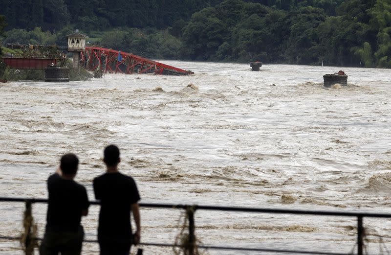 People watch the swollen Kuma River after torrential rain in Kuma town