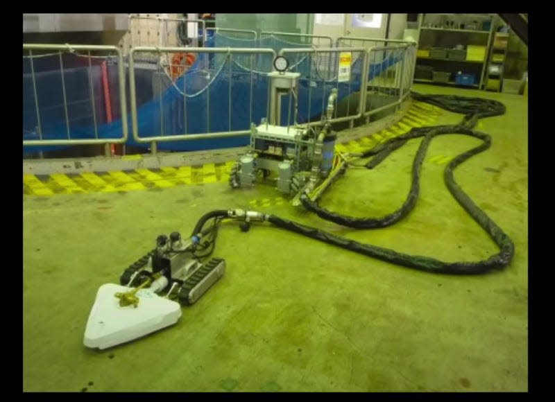 A pair of robots with long cables attached are used to suck up radioactive debris at Fukushima. 