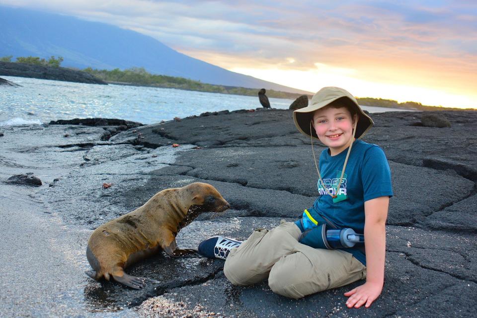A little boy with a baby sea lion in the Galapagos