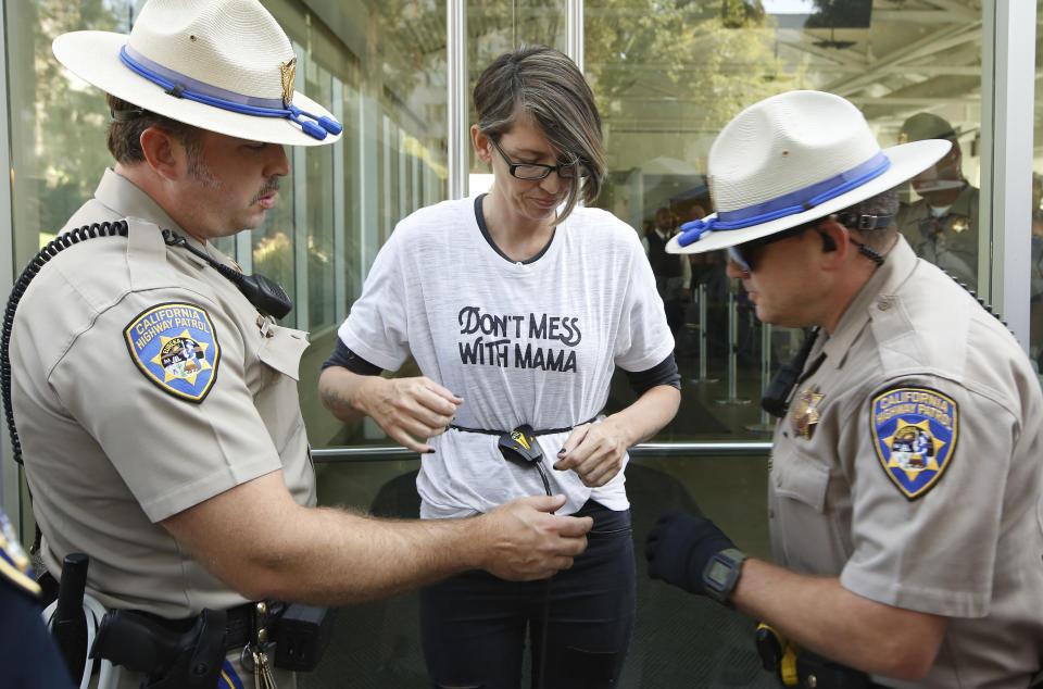 California Highway Patrol officers take into custody an opponent of recently passed legislation to tighten the rules on giving exemptions for vaccinations, after she cabled herself to the doors of the state Capitol in Sacramento, Calif., Monday, Sept. 9, 2019. The state Assembly approved the companion bill, Monday, with changes demanded by Gov Gavin Newsom as a condition of signing the controversial vaccine bill SB276 which was passed by the Legislature last week. (AP Photo/Rich Pedroncelli)