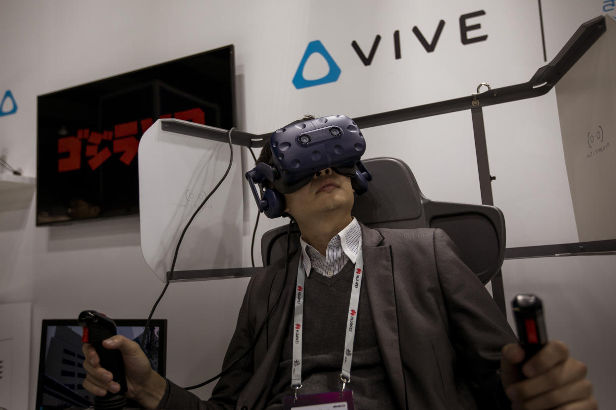 A visitor uses a VR gear of HTC-VIVE, at the Mobile World Congress wireless show, in Barcelona, Spain, Tuesday, Feb. 26, 2019. Futuristic technology known as the metaverse, which immerses users in a digital simulation of the real world, is far from fully formed.