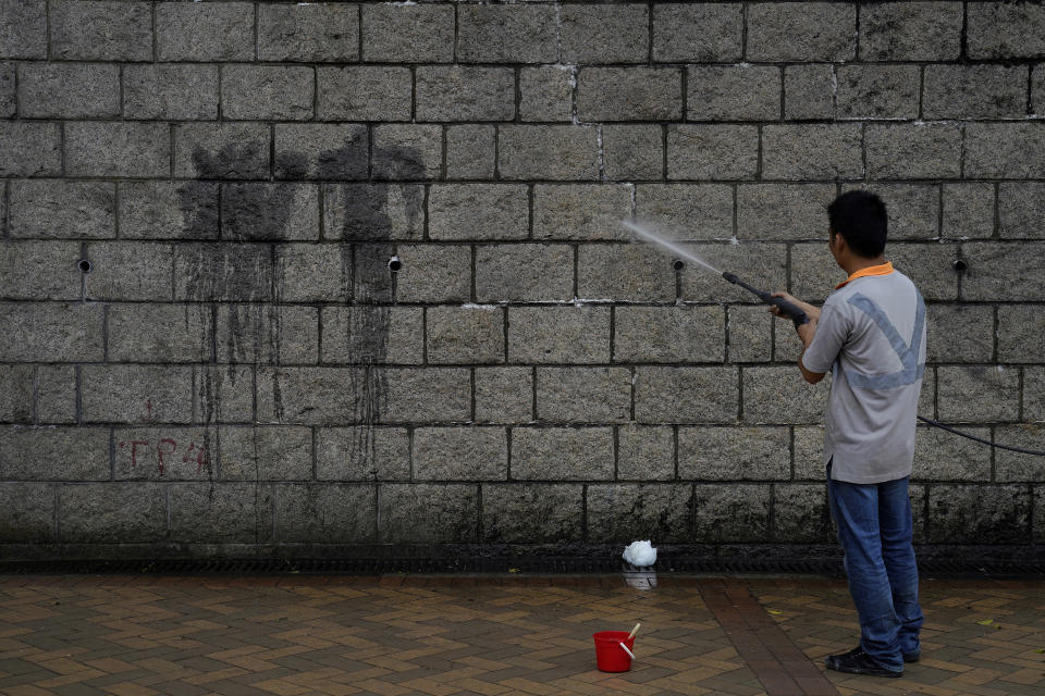 In this Sept. 18, 2019, photo, a cleaner attempts to remove an anti-government graffiti by using a high-pressure water gun in Hong Kong. As Hong Kong enters its fourth month of steady protests, the city is embracing for another violent weekend prior to the upcoming 70th National Day on Oct. 1. (AP Photo/ Vincent Yu)